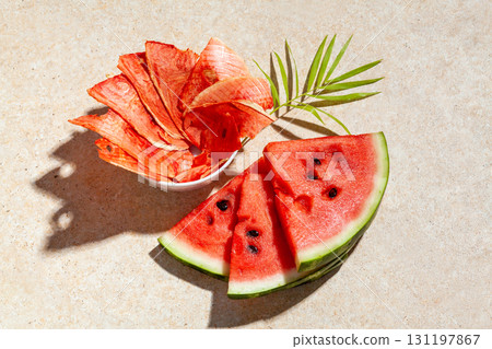 Winter supplies: slices of dried watermelon with fresh pieces on light background with deep shadow Winter supplies: slices of dried watermelon with fresh pieces on light background with deep shadow 131197867