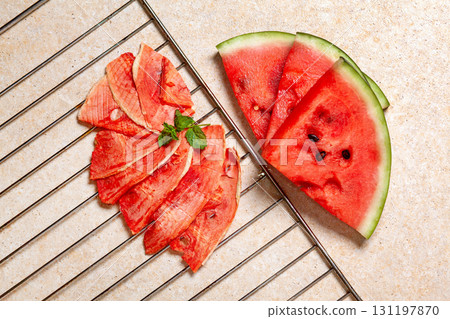 Winter supplies: slices of dried watermelon with fresh pieces on light background with grid Winter supplies: slices of dried watermelon with fresh pieces on light background with grid 131197870