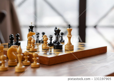 Wooden chess pieces on a board game, on vintage table, selective focus Wooden chess pieces on a board game, on vintage table, selective focus 131197905