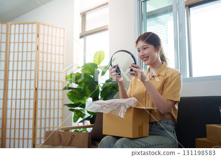 Unboxing: Young woman excitedly opening package from online shopping Unboxing: Young woman excitedly opening package from online shopping 131198583