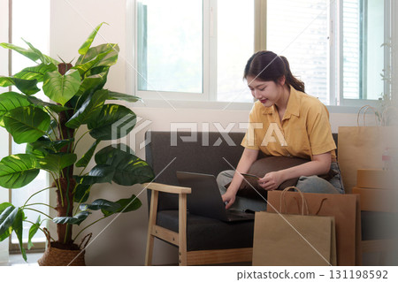 Online Shopping. Young woman browsing laptop surrounded by shopping bags. Online Shopping. Young woman browsing laptop surrounded by shopping bags. 131198592