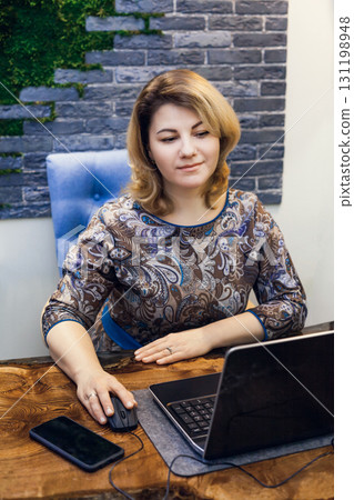 A young woman interior designer is working in her office at a computer. Green office, live plants in an office space A young woman interior designer is working in her office at a computer. Green office, live plants in an office space 131198948