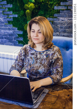 A young woman interior designer is working in her office at a computer. Green office, live plants in an office space 131198951