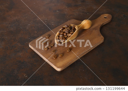 Coffee beans in a wooden scoop isolated on a dark background. Roasted coffee beans isolated. A wooden scoop with coffee. Coffee beans in a wooden scoop isolated on a dark background. Roasted coffee beans isolated. A wooden scoop with coffee. 131199644