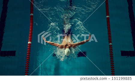 Swimmer mastering butterfly stroke with powerful arm extension in competitive lane 131199885