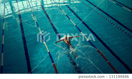 Focused swimmer executing butterfly stroke in indoor lane with powerful energy 131199886