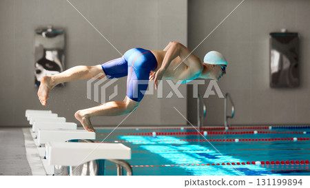 Swimmer diving from start block into pool with powerful push-off Swimmer diving from start block into pool with powerful push-off 131199894