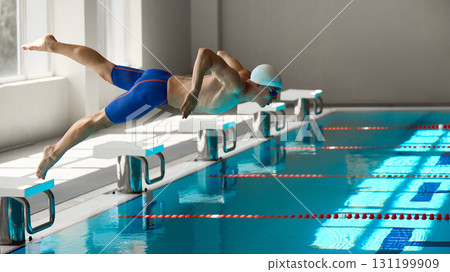 Male swimmer diving into pool with dynamic motion during start phase 131199909