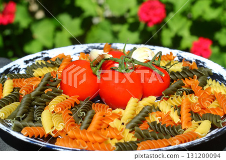 Colorful various raw fusilli on black plate 131200094