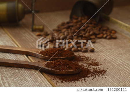 Coffee beans and ground coffee in wooden spoons on brown background. Flat lay. 131200111