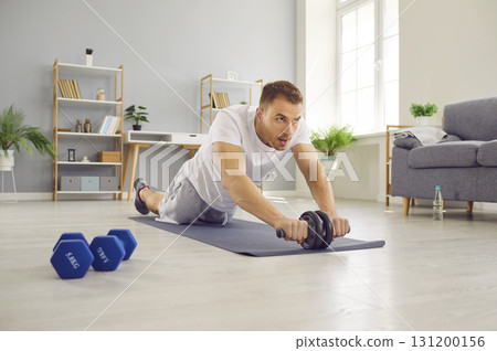 Handsome middle aged man doing exercise with abs wheel on mat Handsome middle aged man doing exercise with abs wheel on mat 131200156