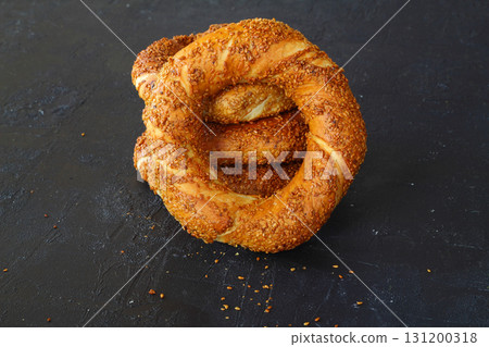 Turkish simit bagel dusted with sesame seeds on a black background. 131200318