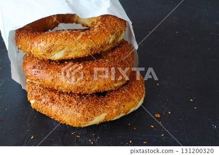 Turkish simit bagel dusted with sesame seeds on a black background. 131200320