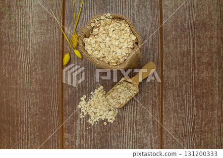 Oat flake in a sack and spoon on the wooden table 131200333