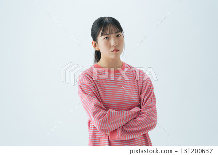 A teenage girl in casual wear with her arms crossed and worried 131200637