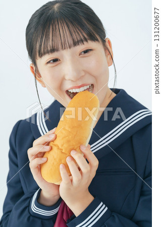 A female student wearing a sailor uniform eating a roll A female student wearing a sailor uniform eating a roll 131200677