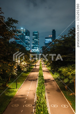 skyscrapers of night Bangkok city with Benchakitti park tracks, illuminated pathways and walkways with people walking and jogging, harmony of bustling city and nature 131201360
