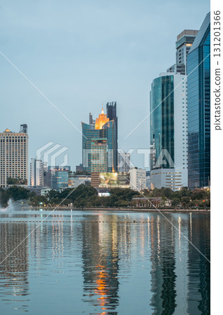 evening panorama of Bangkok city skyline with skyscrapers and Benchakitti park lake, vibrant cityscape view with reflections over pond water at dusk evening panorama of Bangkok city skyline with skyscrapers and Benchakitti park lake, vibrant cityscape view with reflections over pond water at dusk 131201366