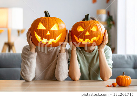 Two people hold carved pumpkins in front of their faces for Halloween fun.. 131201715
