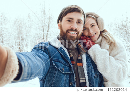 Smiling man making selfie with his girl friend in a winter forest Smiling man making selfie with his girl friend in a winter forest 131202014