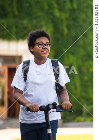 Smiling teen in white tshirt on a scooter looking contented Smiling teen in white tshirt on a scooter looking contented 131202281