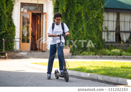 Smiling teen in white tshirt on a scooter looking contented Smiling teen in white tshirt on a scooter looking contented 131202283