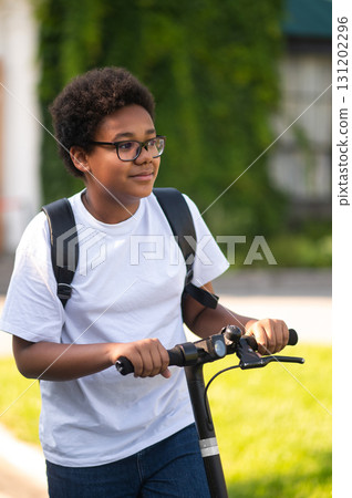 Curly-haired african american teen on the electric scooter Curly-haired african american teen on the electric scooter 131202296