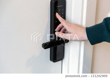 A human hand presses buttons with numbers to enter a code to open the door. A human hand presses buttons with numbers to enter a code to open the door. 131202909