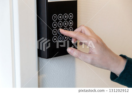 A human hand presses buttons with numbers to enter a code to open the door. 131202912