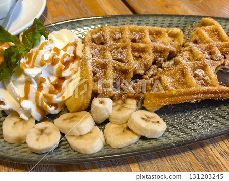 Indulging in delicious waffles with banana and whipped cream delight Indulging in delicious waffles with banana and whipped cream delight 131203245
