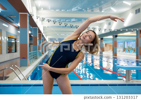 Positive slim short-haired woman doing warming up exercises before swimming in the pool 131203317