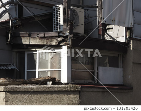 一片腐爛的樹木、破舊的窗戶和顯示出生命跡象的建築物的景觀。 一片腐爛的樹木、破舊的窗戶和顯示出生命跡象的建築物的景觀。 131203420