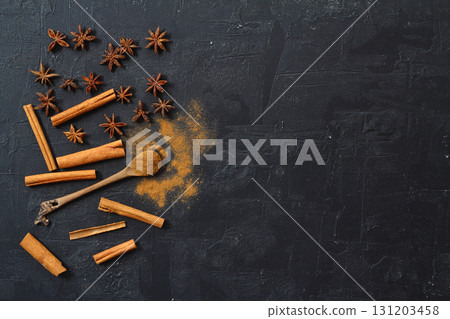 Aromatic cinnamon sticks, cinnamon powder and anise on black table, flat lay. Space for text Aromatic cinnamon sticks, cinnamon powder and anise on black table, flat lay. Space for text 131203458