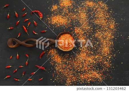 A wooden spoon with chili pepper on a dark wooden table. Universal seasoning for all dishes. 131203462