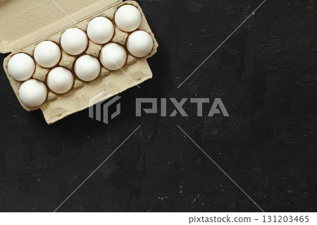 Raw White Eggs in a paper box on a black background, top view. Copy Space for text. Raw White Eggs in a paper box on a black background, top view. Copy Space for text. 131203465
