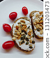 Whole grain toast with cream cheese, seeds, peanuts and cherry tomatoes. Whole grain toast with cream cheese, peanuts and mixed seeds, served with fresh cherry tomatoes on a white plate. Homemade vege 131203473