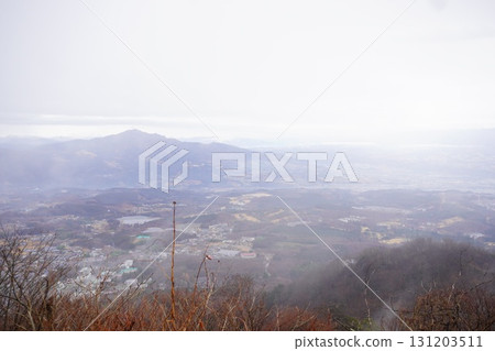 A panoramic photo of a natural landscape with mountains and a cityscape seen from afar under a cloudy sky A panoramic photo of a natural landscape with mountains and a cityscape seen from afar under a cloudy sky 131203511
