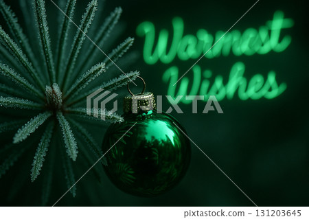 Warmest Wishes text with glowing green bauble ornament on festive dark background. 131203645