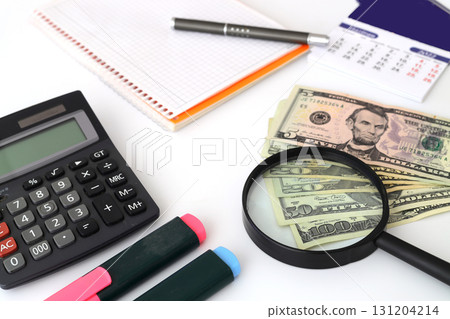 Banknotes spread out on a table with a calculator and a magnifying glass. Banknotes spread out on a table with a calculator and a magnifying glass. 131204214