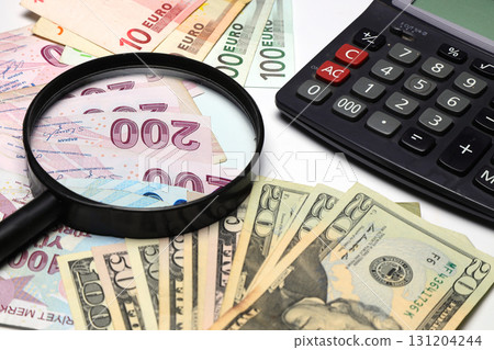 Banknotes spread out on a table with a calculator and a magnifying glass. Banknotes spread out on a table with a calculator and a magnifying glass. 131204244