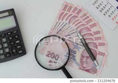 Turksh Lira banknotes of various color, pattern and value on white background. with magnifying glass Turksh Lira banknotes of various color, pattern and value on white background. with magnifying glass 131204676