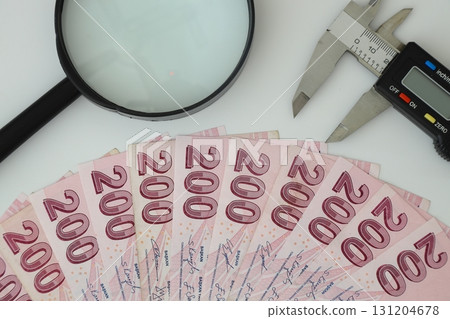 Turksh Lira banknotes of various color, pattern and value on white background. with caliper and magnifying glass Turksh Lira banknotes of various color, pattern and value on white background. with caliper and magnifying glass 131204678