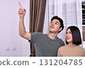 A couple enjoys their time together while pointing at something interesting indoors. 131204785
