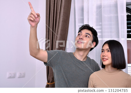 A couple enjoys their time together while pointing at something interesting indoors. A couple enjoys their time together while pointing at something interesting indoors. 131204785