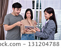 Three professionals engaged in a lively discussion over a tablet. 131204788