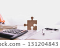 Creative workspace with puzzle piece, calculator, and pens, symbolizing problem-solving and teamwork in business. 131204843