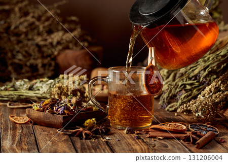 Hot herbal tea is poured into a glass mug. 131206004