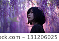 Girl looking up at wisteria flowers 131206025