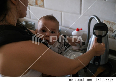 Mother cooking with baby in carrier 131206546