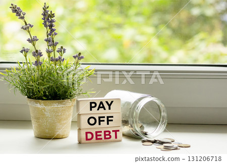 Pay off the debt with a text message on wooden blocks, next to a jar of coins Pay off the debt with a text message on wooden blocks, next to a jar of coins 131206718
